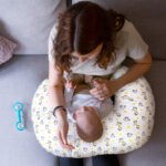 New Mom holding baby on fresh hug freshug Giraffe Cuddle Nursing Pillow